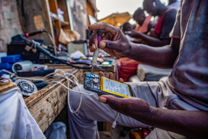 Le quartier « Salle des ventes », à Dakar, est le repère des réparateurs d’objets électroniques et électriques en tout genre. Le long d’un mur, des établis de fortune servent de lieux de travail à une vingtaine de réparateurs de téléphones, télécommandes et autres casques audio. © Jennifer Carlos / Reporterre